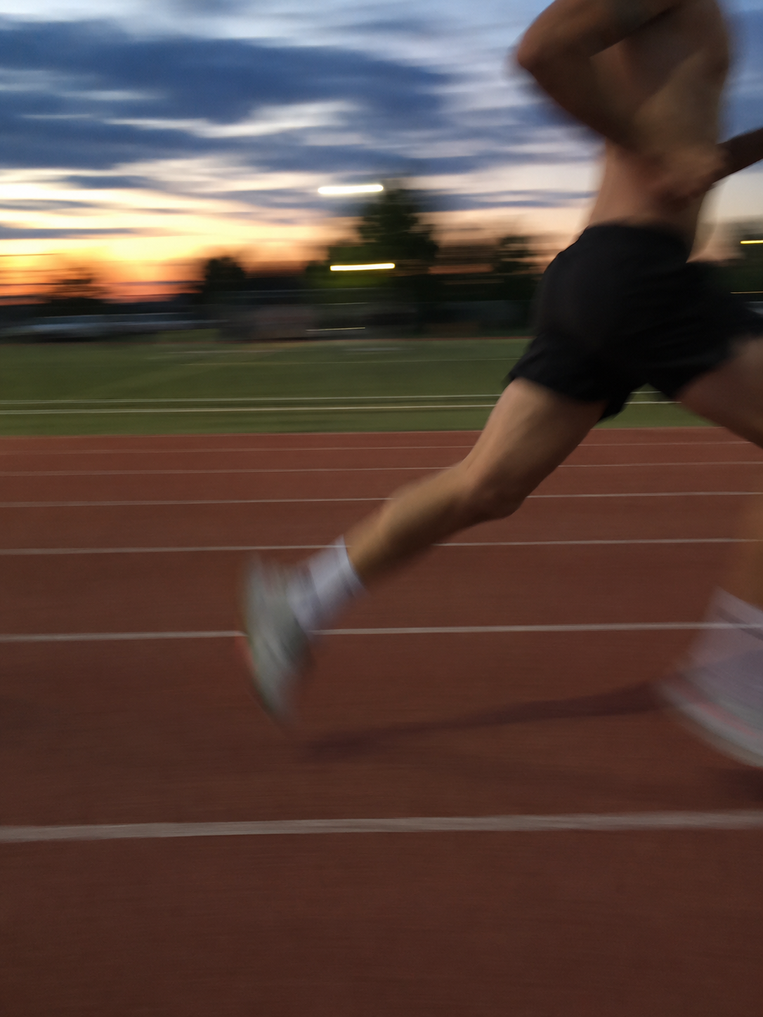 Student athlete sprinting on a track at dusk